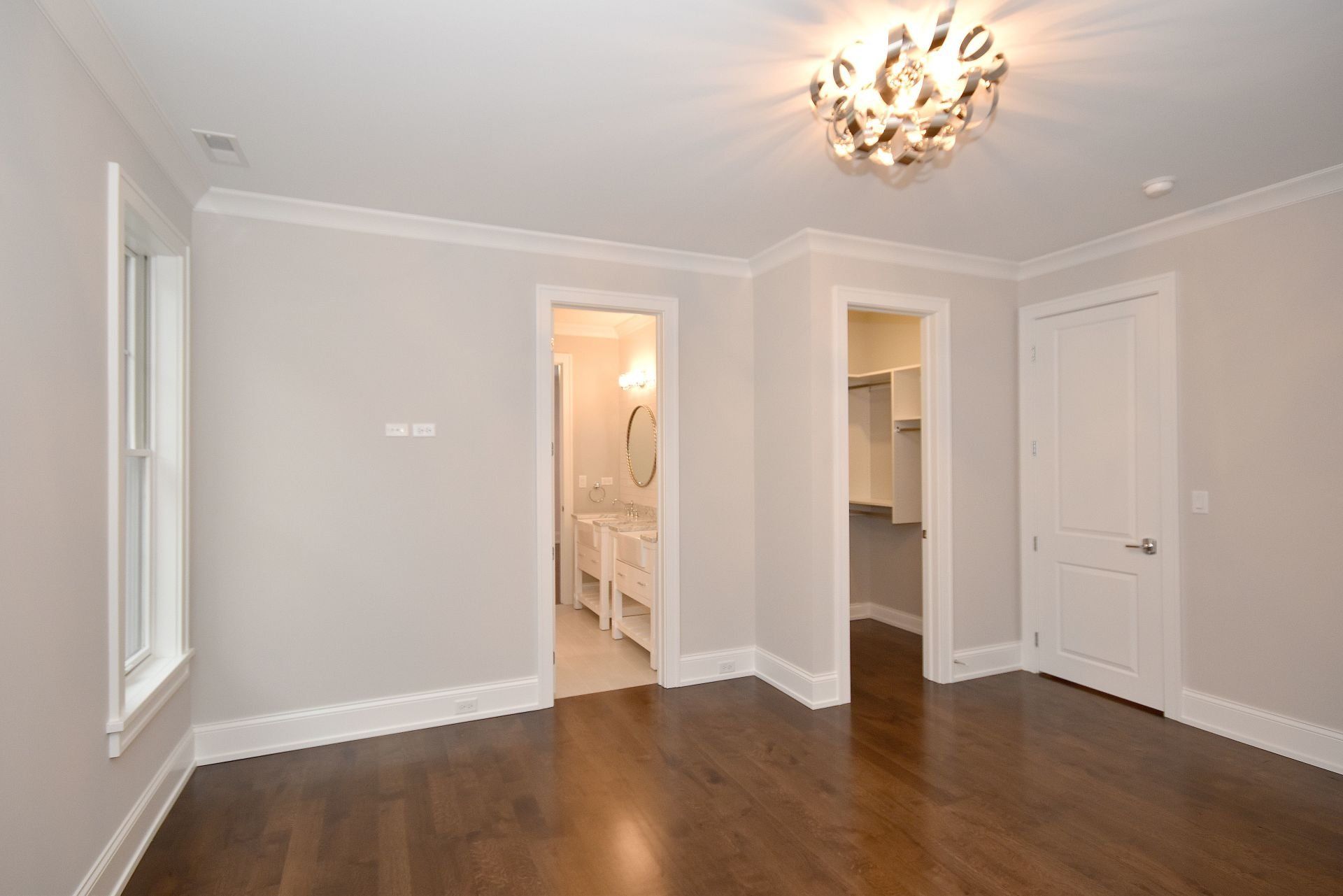 An empty bedroom with hardwood floors and white walls