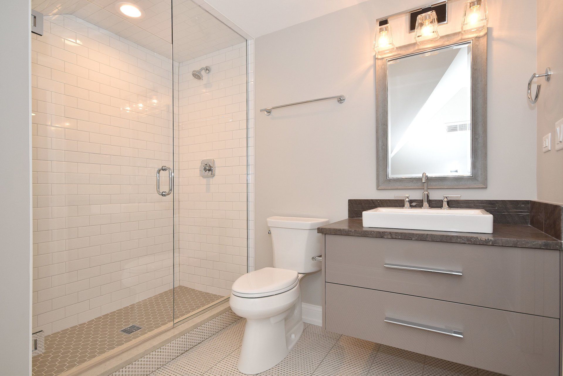 A bathroom with a toilet , sink , shower and mirror.