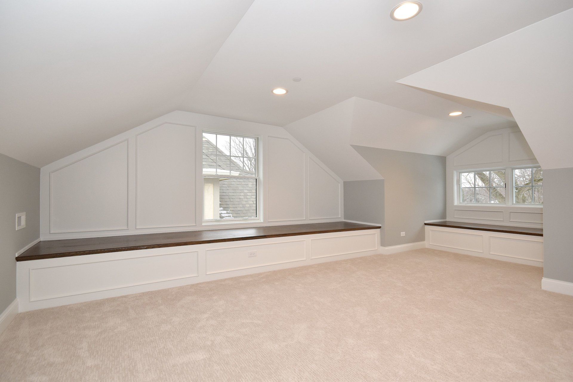An empty room with a window seat and a carpeted floor.