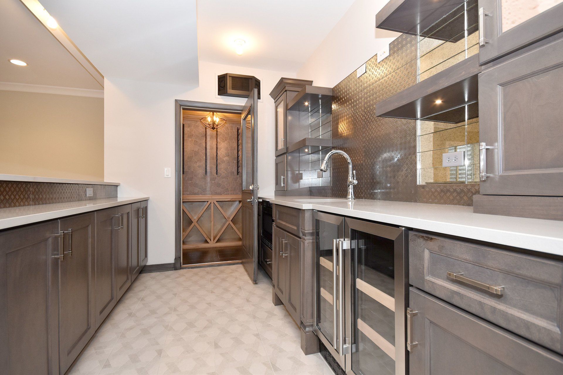 A kitchen with gray cabinets , stainless steel appliances and a wine cooler.