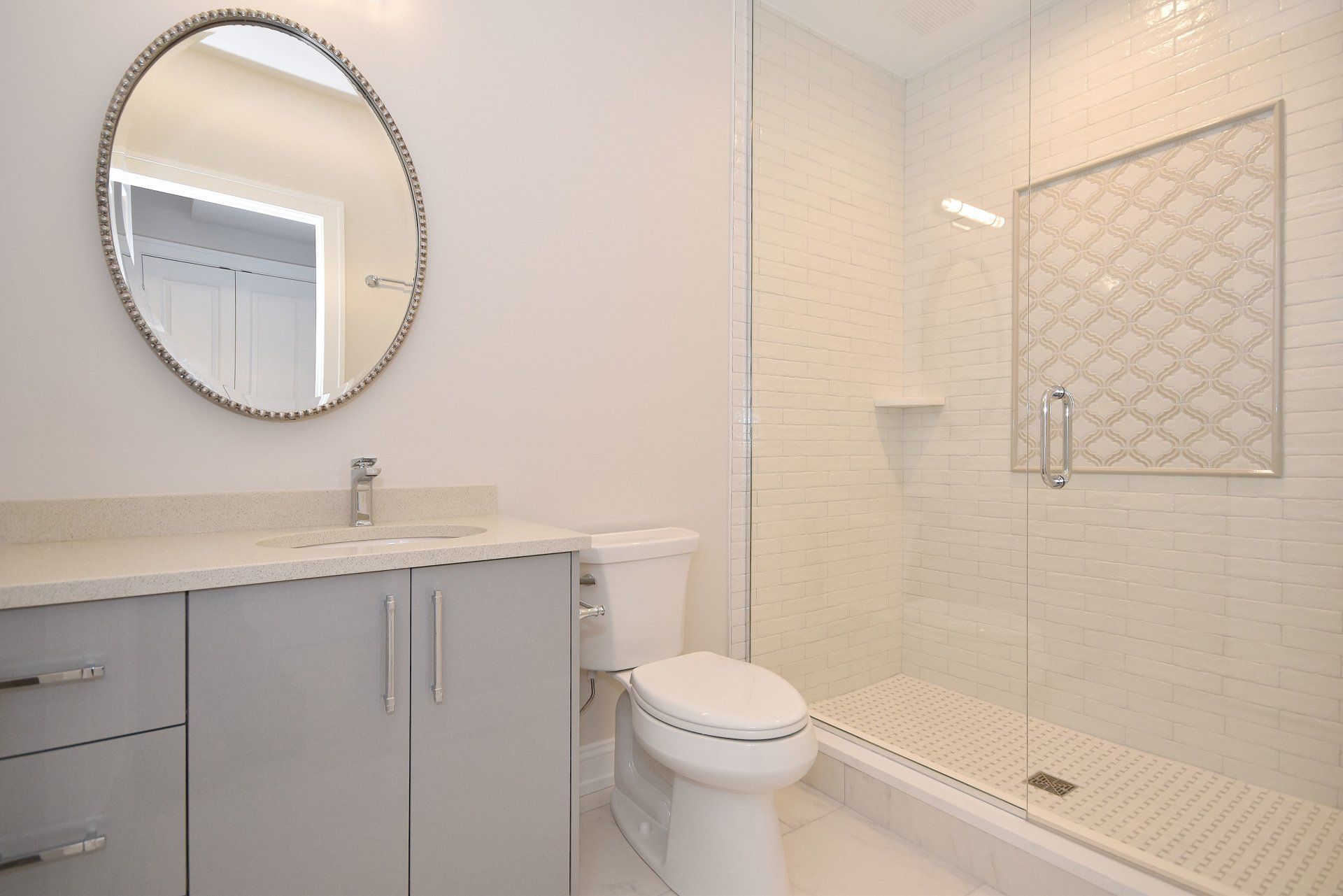 A bathroom with a toilet , sink , mirror and walk in shower.