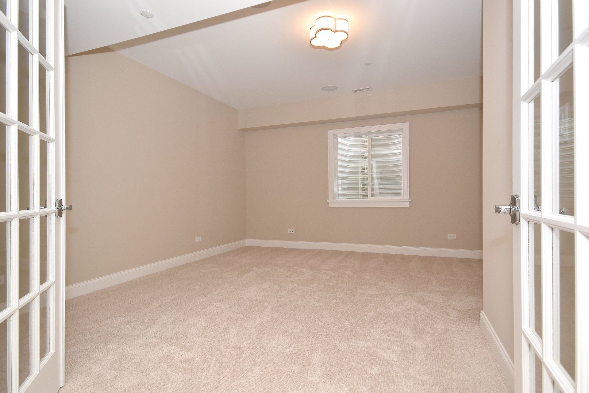 An empty room with a window and french doors