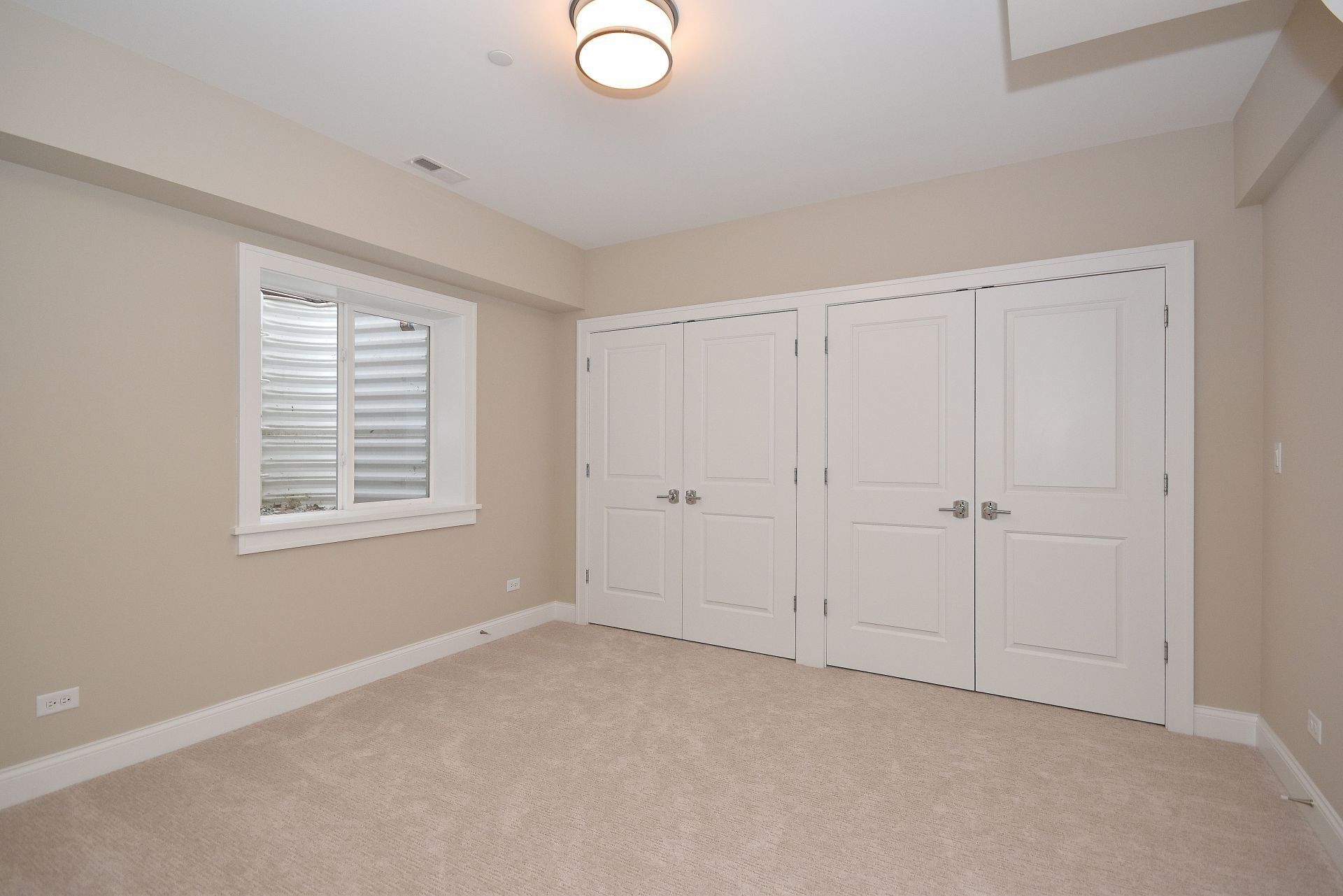 An empty room with white doors and a window