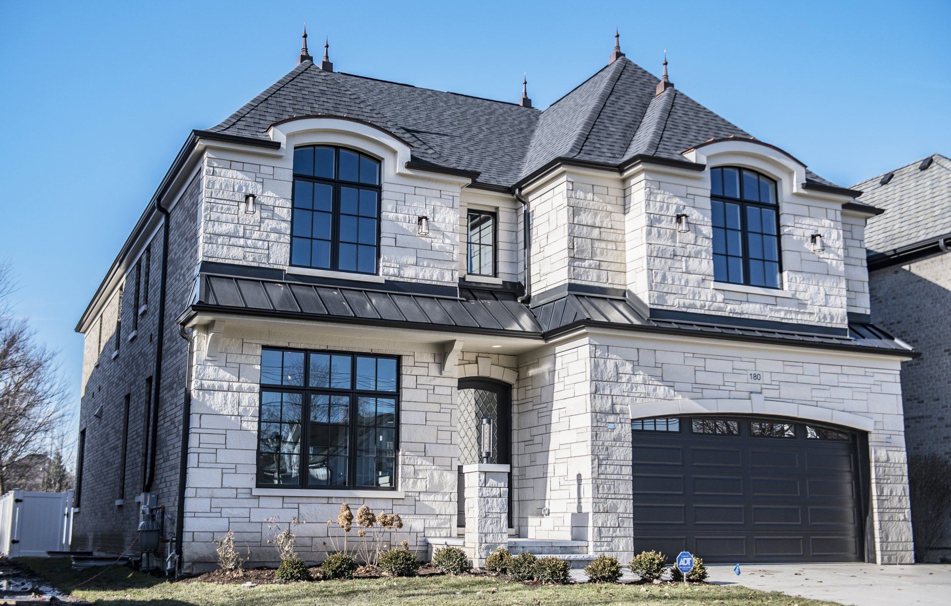 A large white brick house with a black garage door and a gray roof.