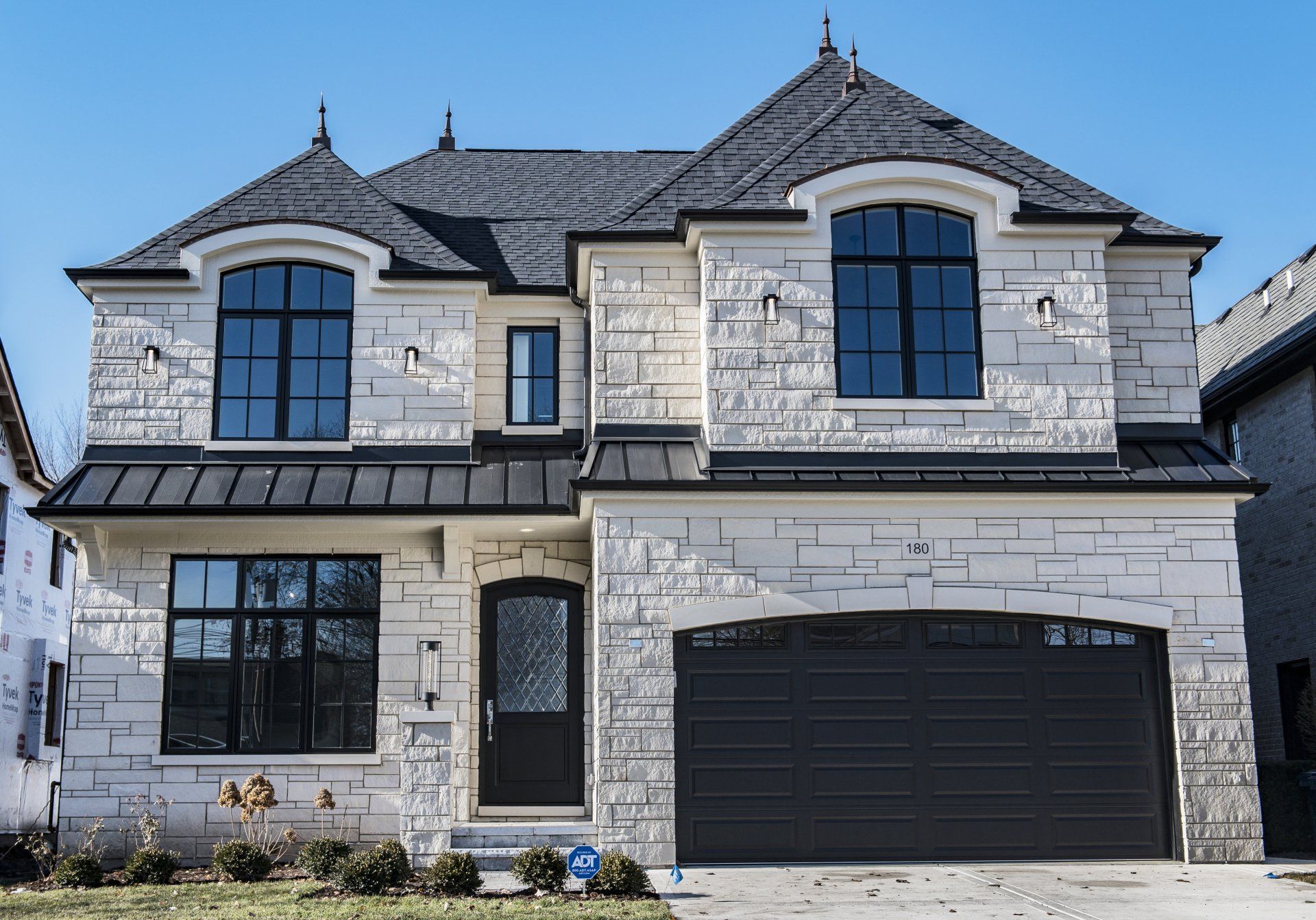 A large white brick house with a black garage door.