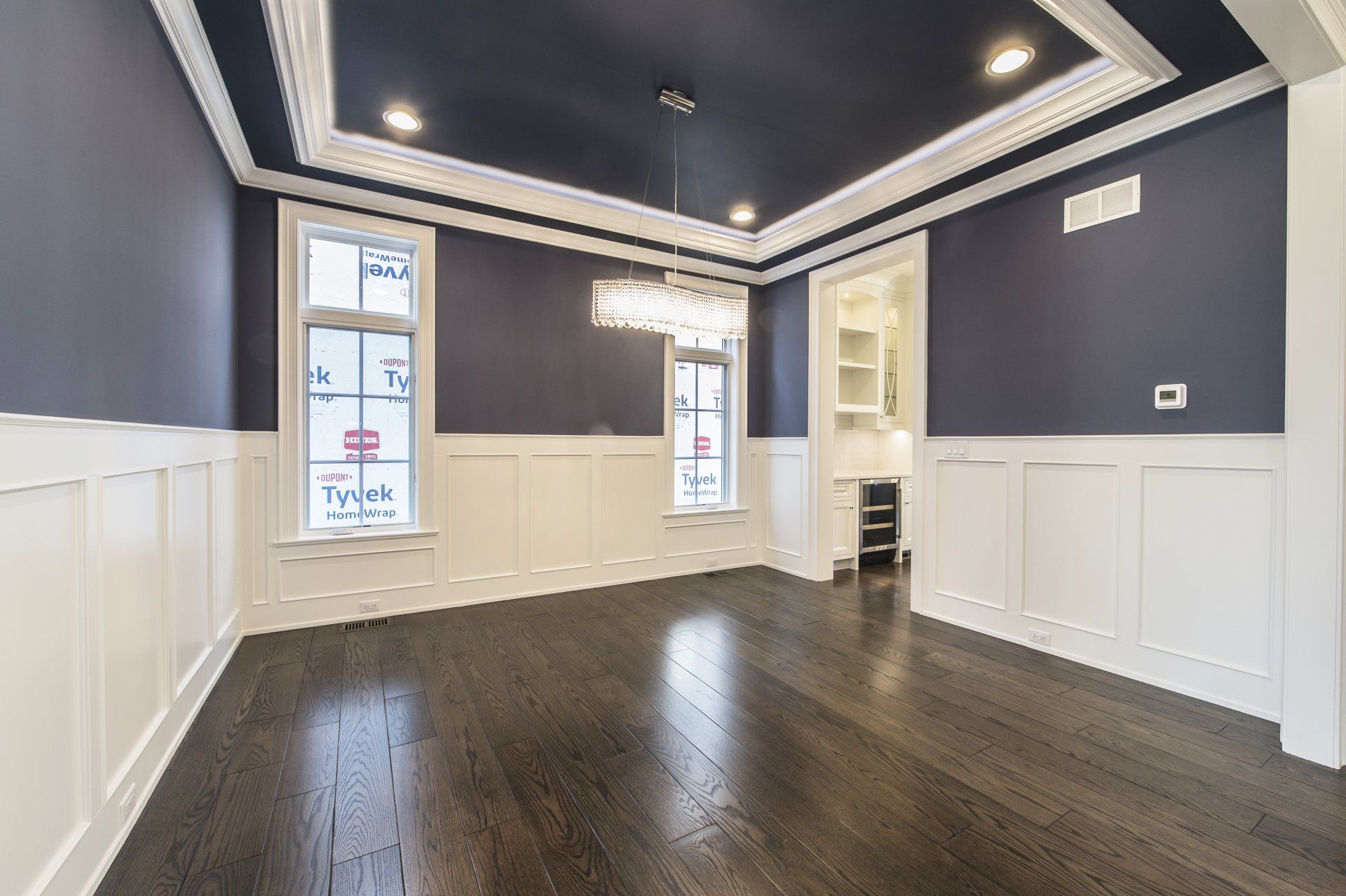 An empty dining room with dark wood floors and blue walls