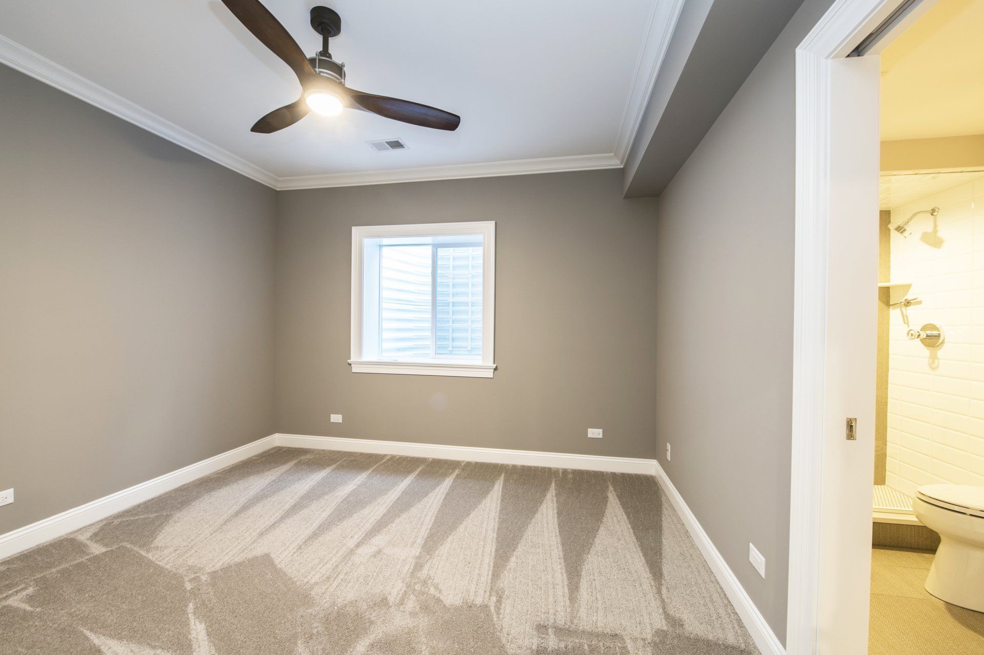 An empty bedroom with a ceiling fan and a window