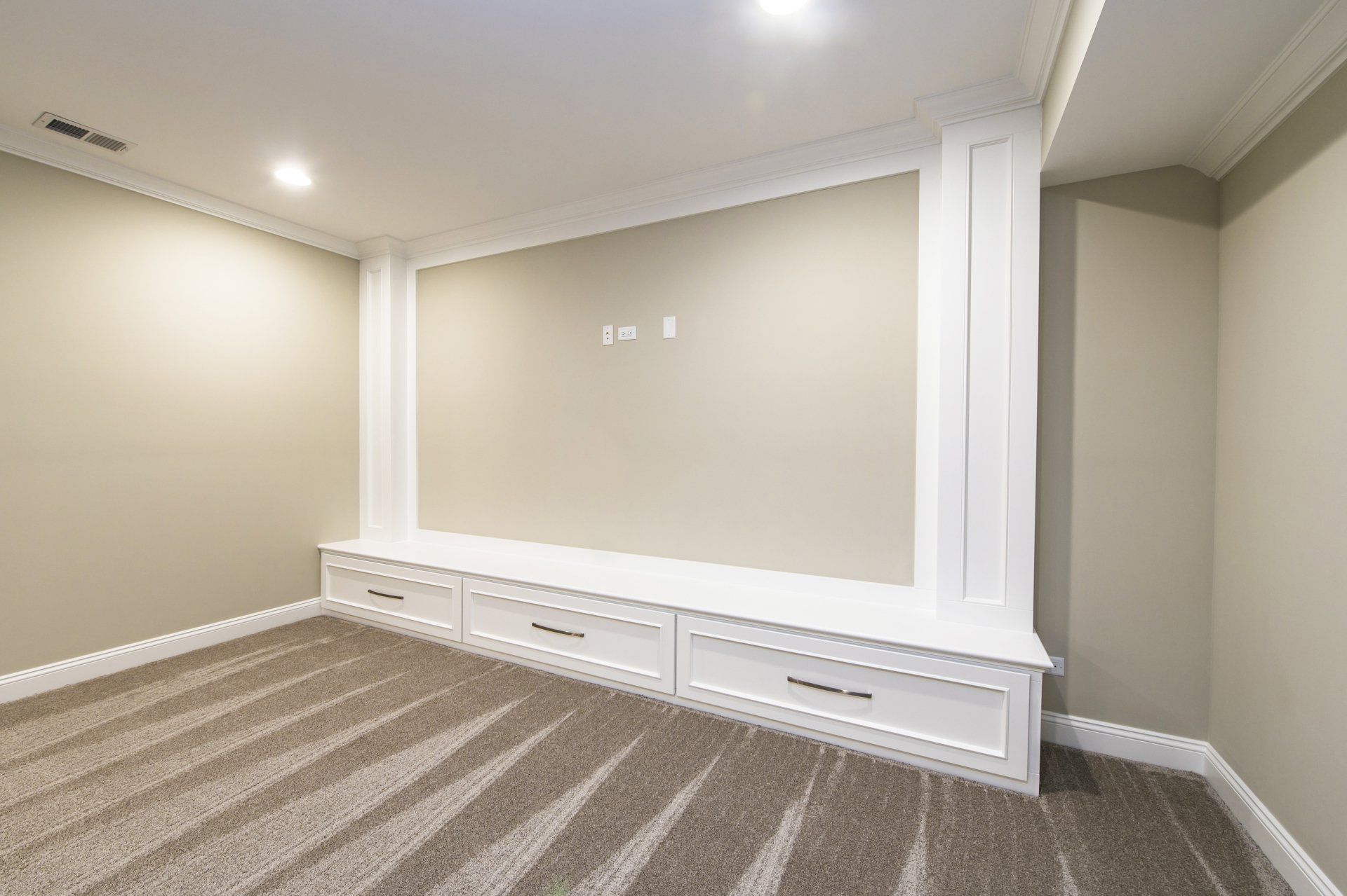 An empty basement with a carpeted floor and a built in entertainment center.