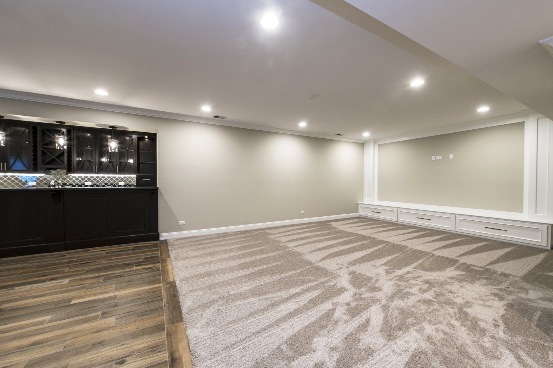 An empty basement with a bar and a carpeted floor.