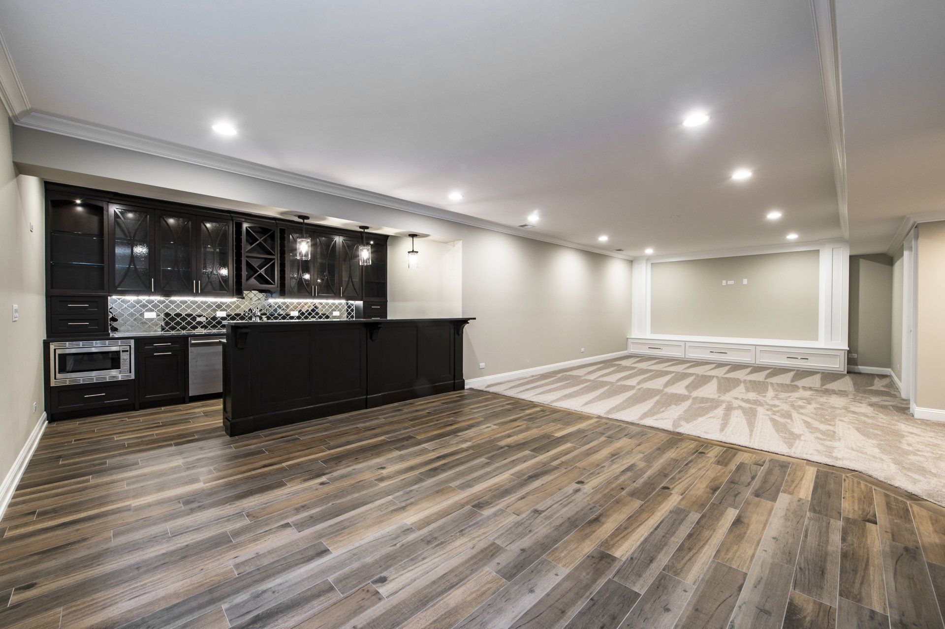 A large empty basement with hardwood floors and a kitchen.