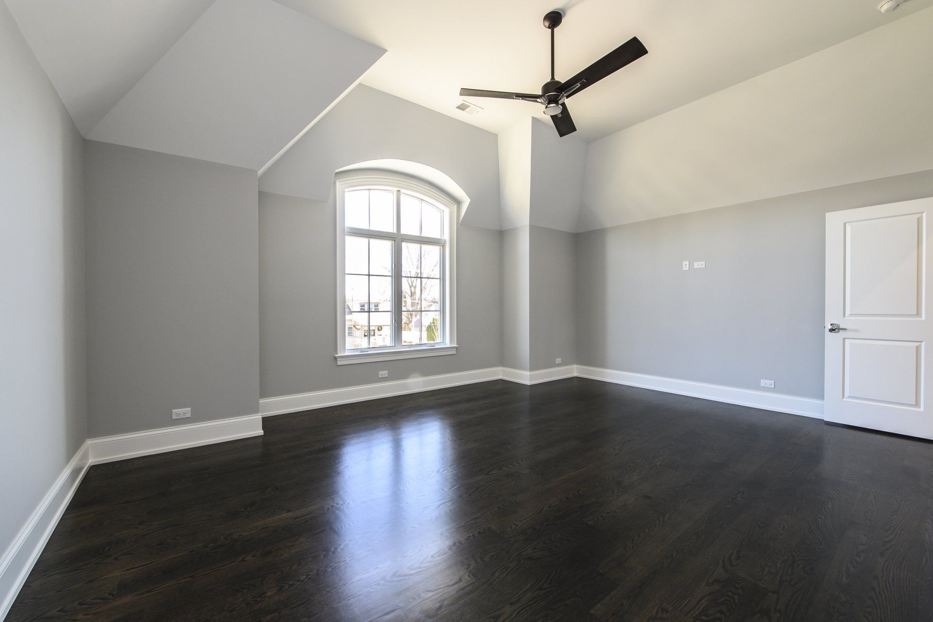 An empty room with a ceiling fan and a window