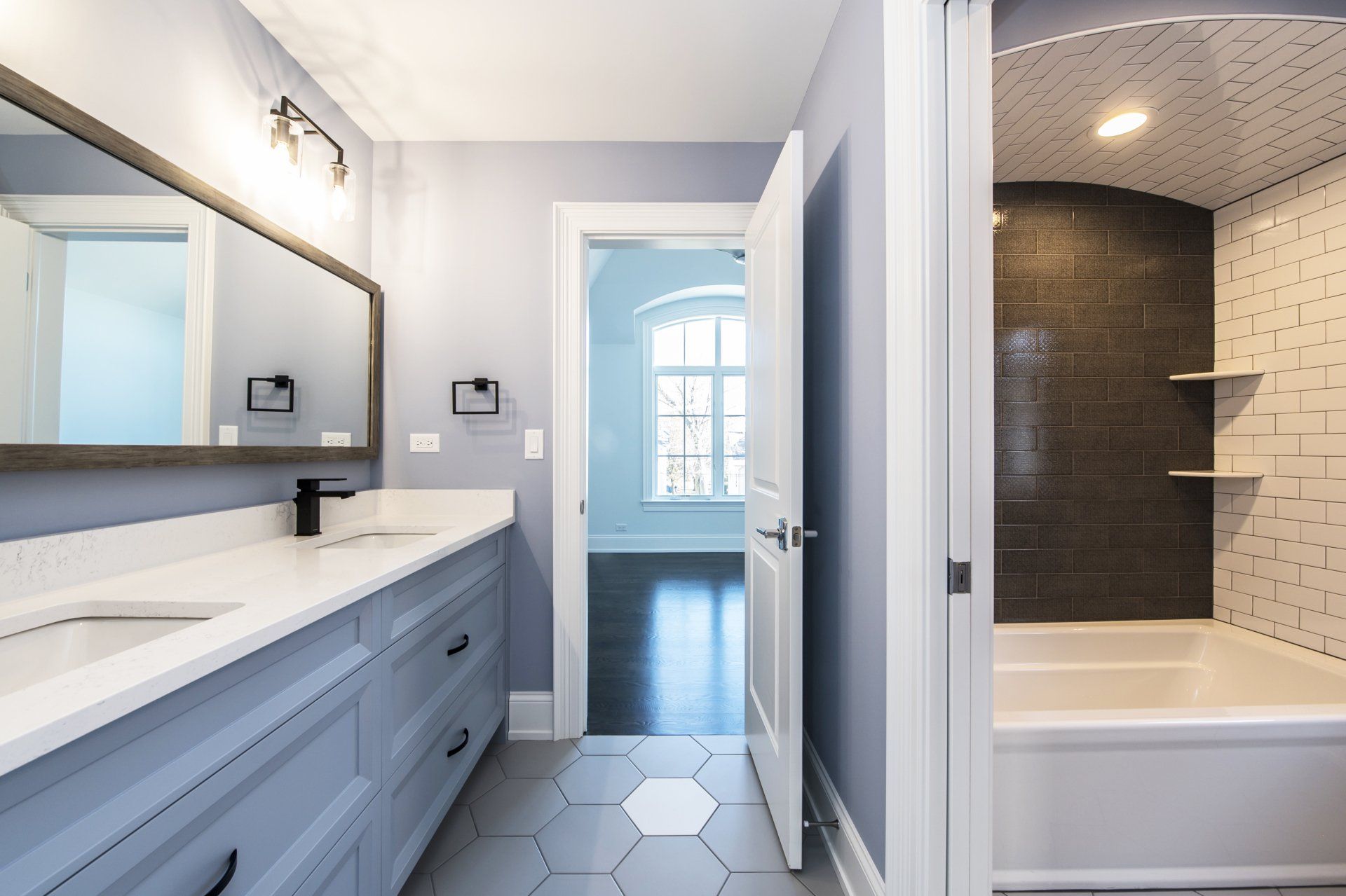A bathroom with two sinks , a tub and a mirror.