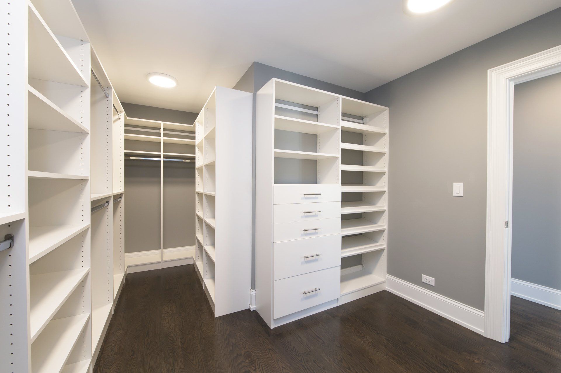 A walk in closet with lots of shelves and drawers
