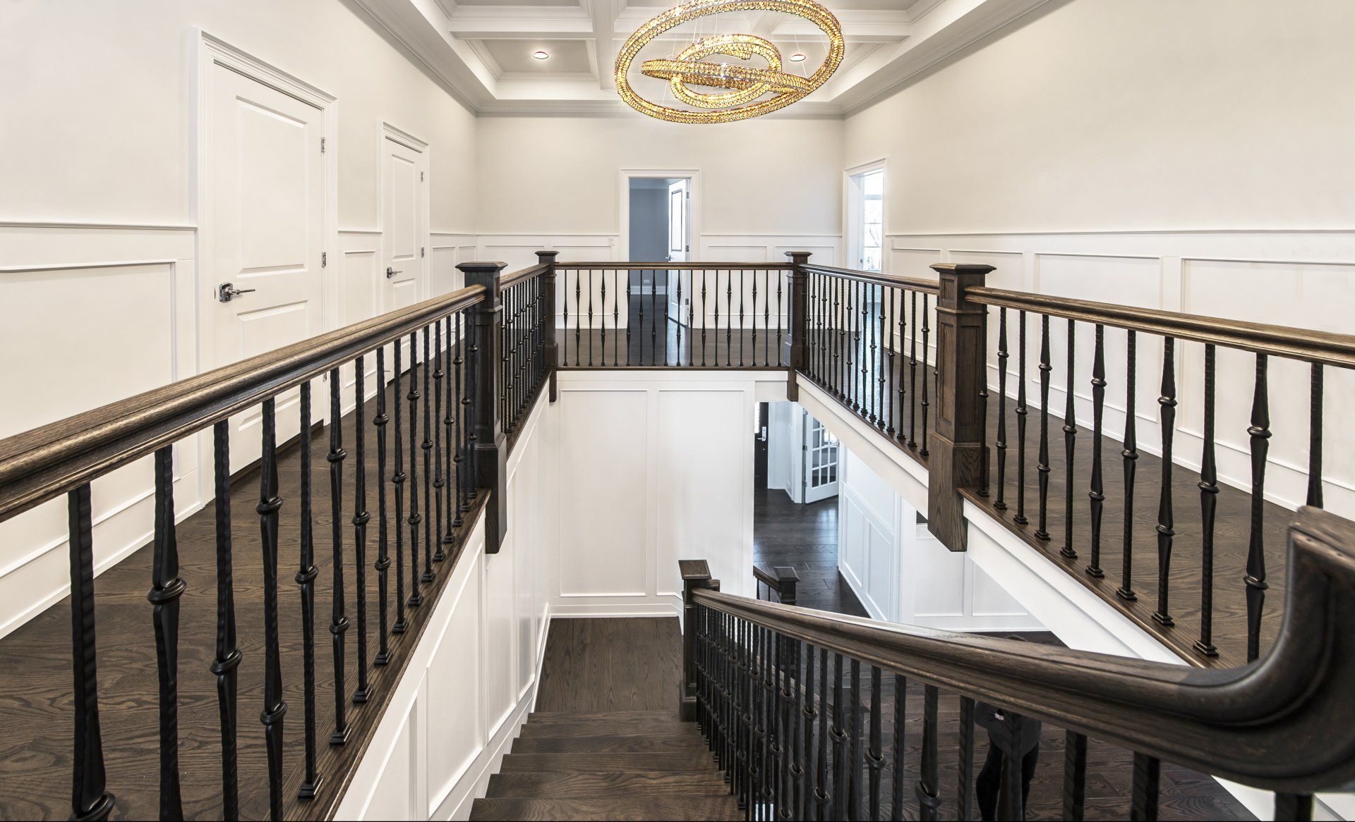 A staircase in a house with a black railing and a chandelier.