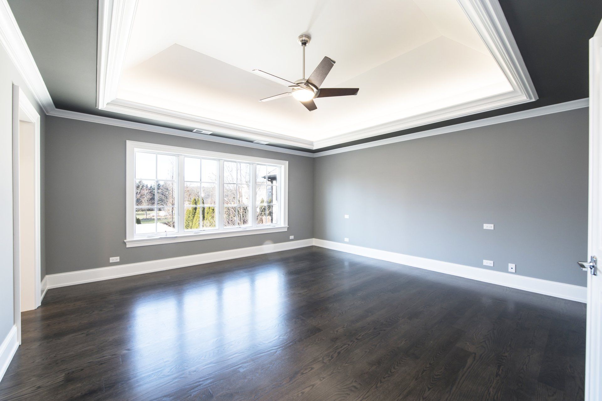 An empty room with hardwood floors and a ceiling fan