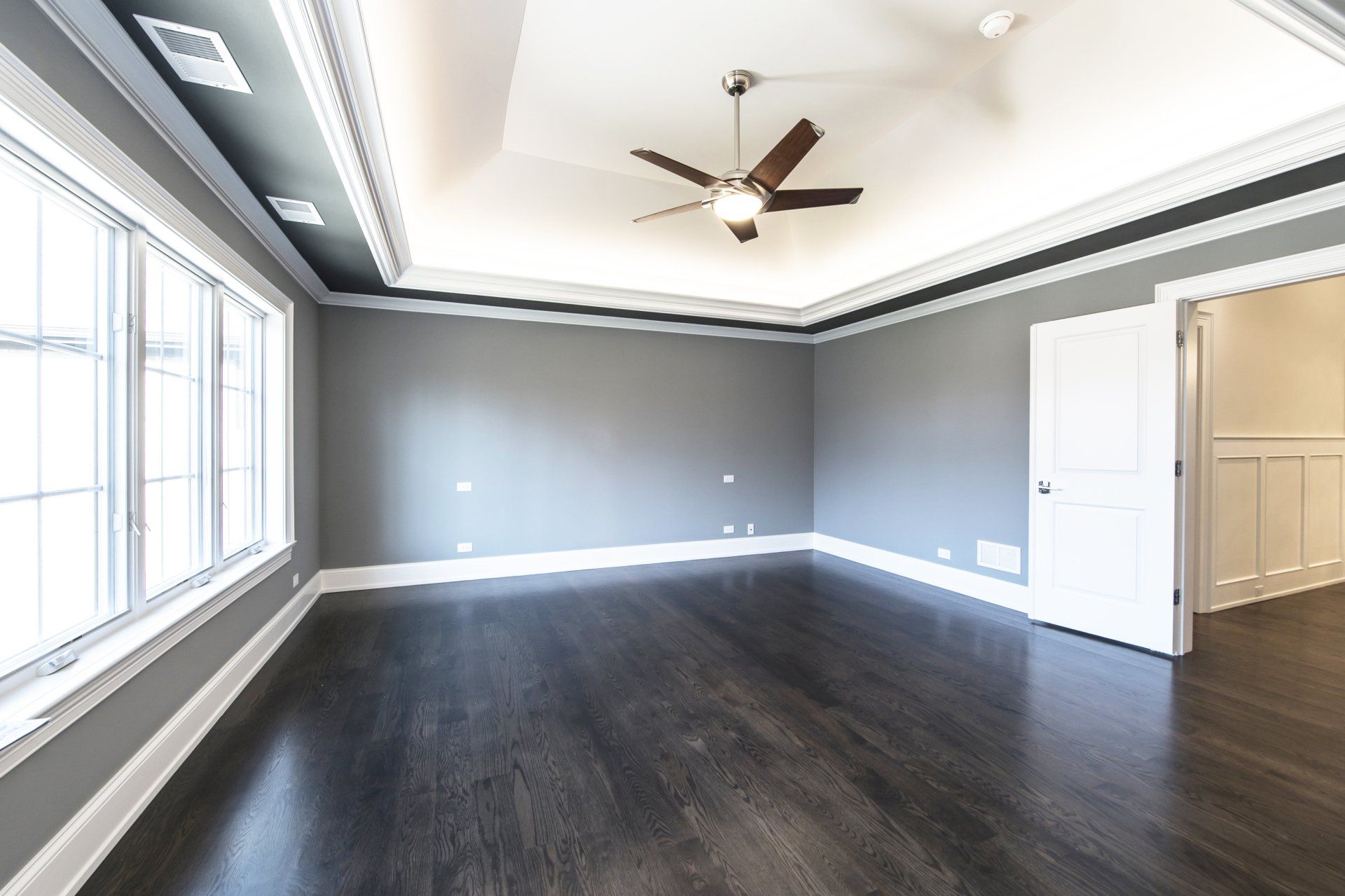 An empty room with a ceiling fan and lots of windows