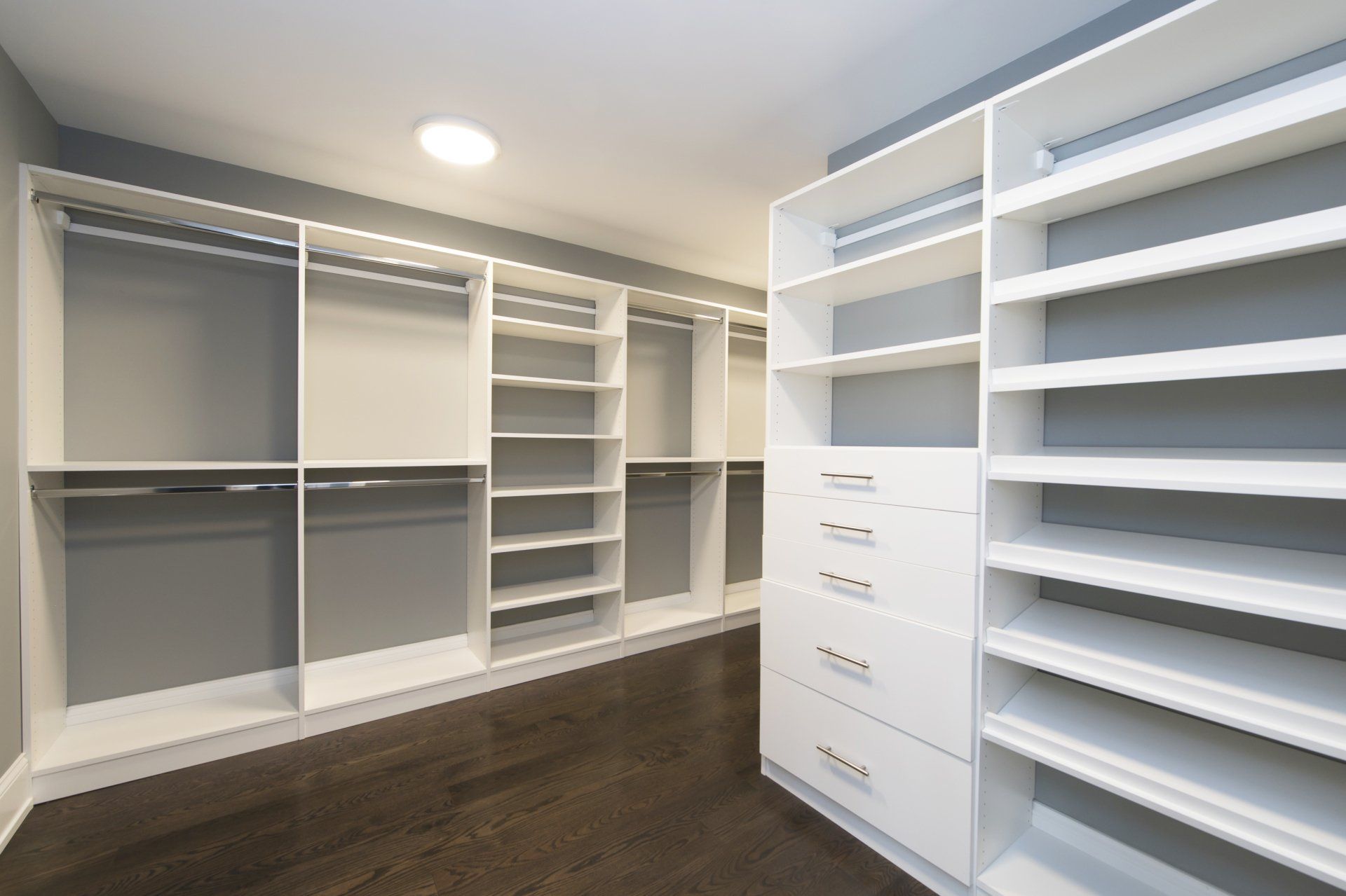 A walk in closet with lots of shelves and drawers.