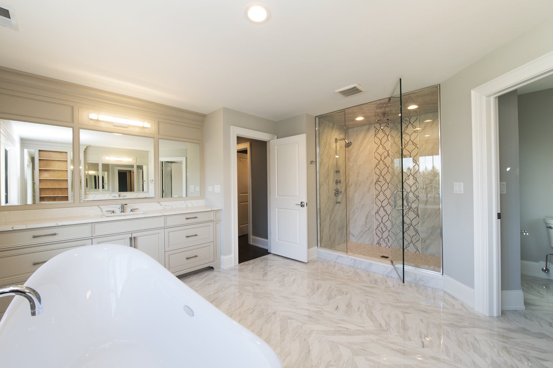 A bathroom with a bathtub , mirrors , and a walk in shower.