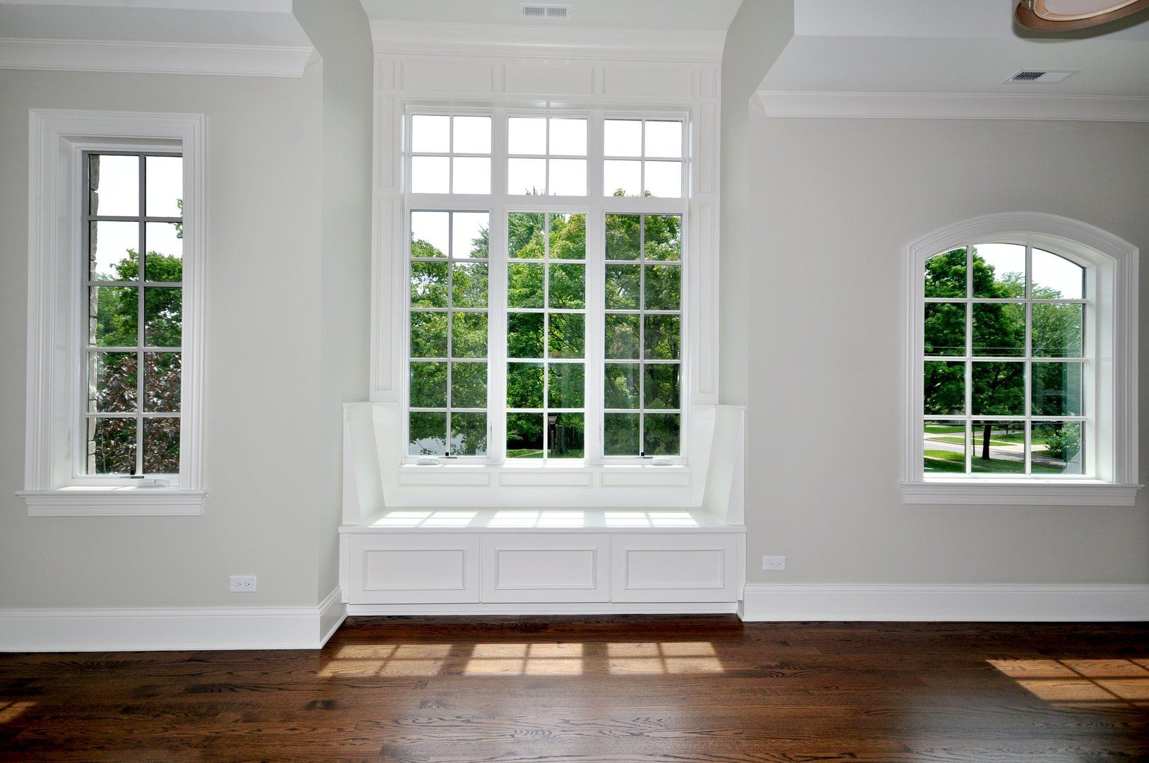 An empty room with three windows and a window seat.