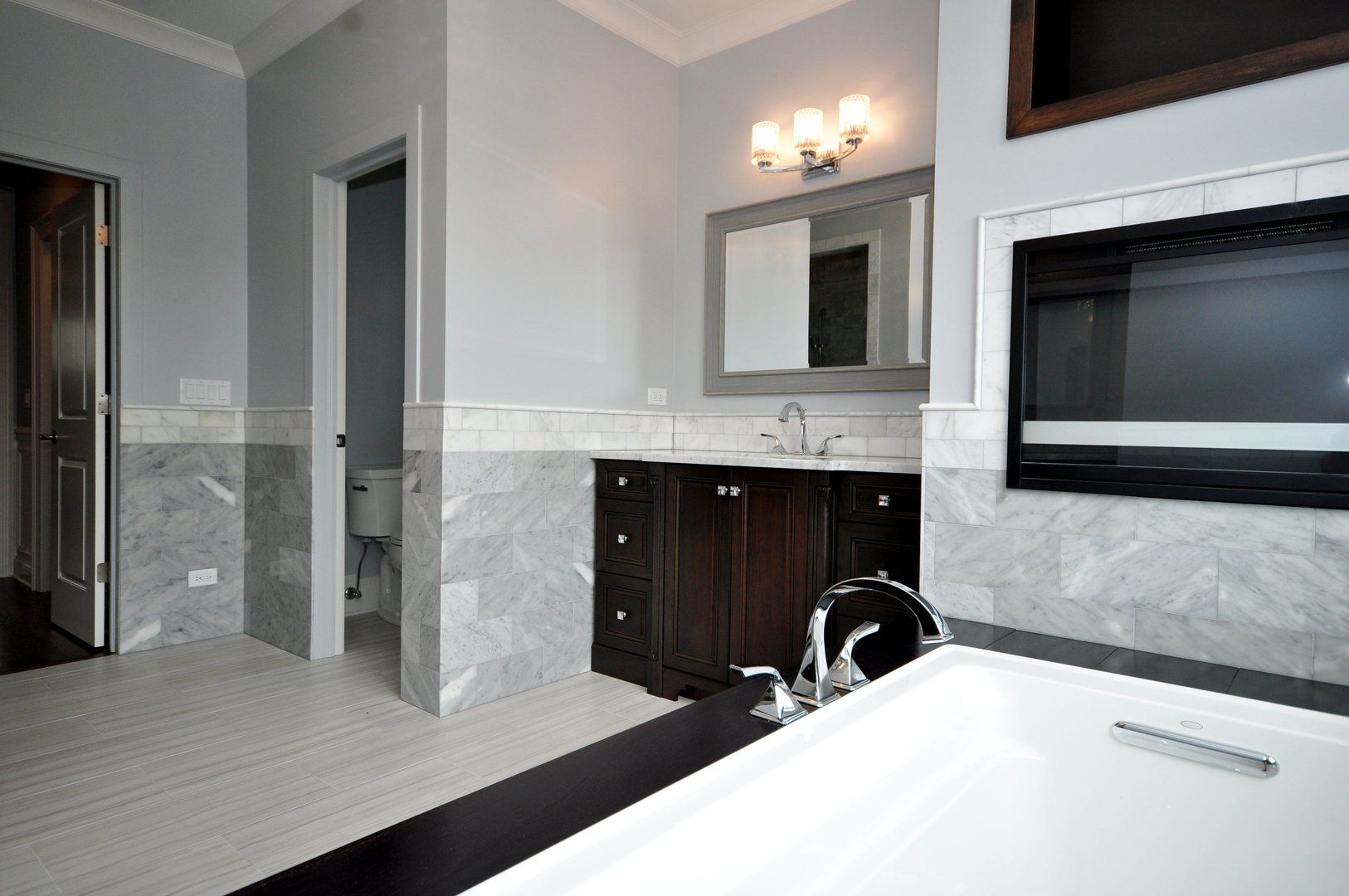 A bathroom with a tub , sink , mirror and fireplace