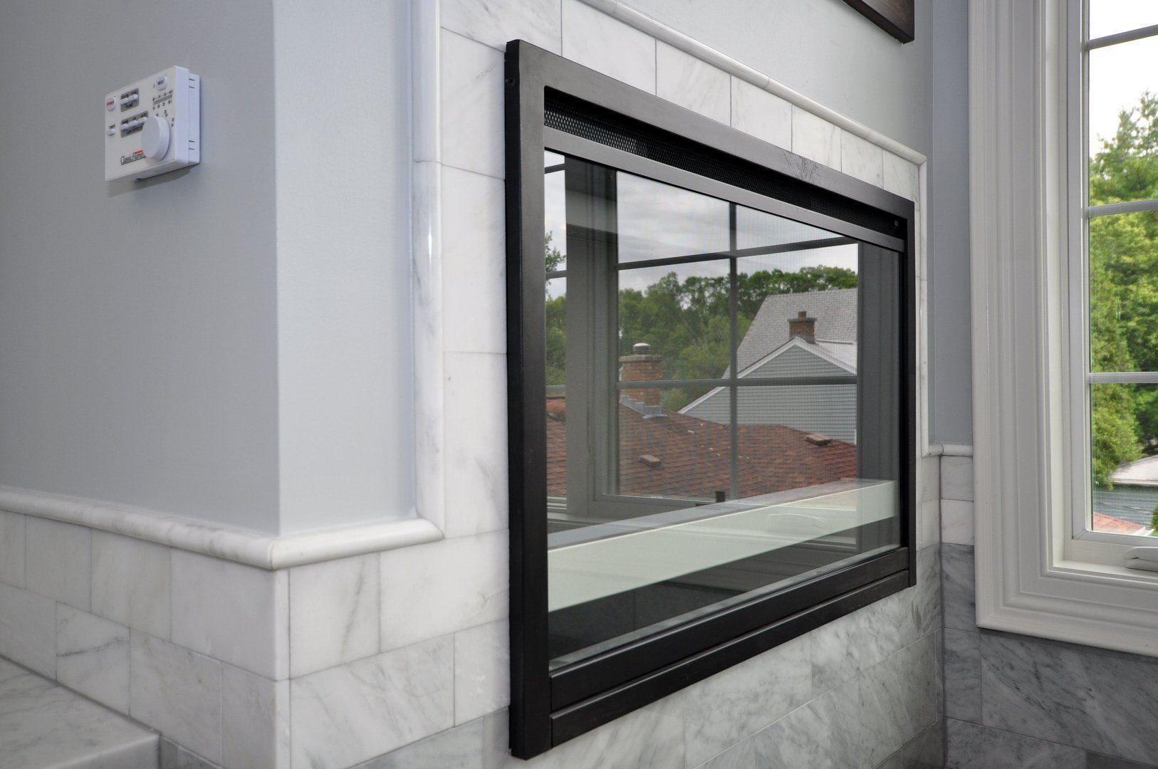 A large mirror is hanging on a wall next to a window.