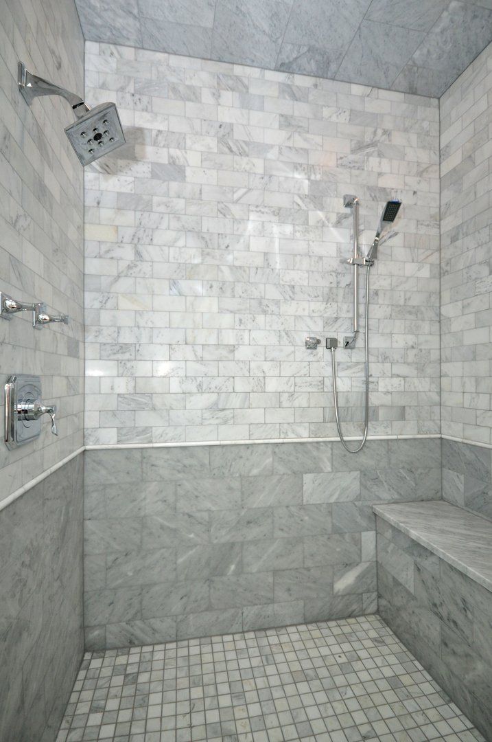 A walk in shower with a bench and a shower head.