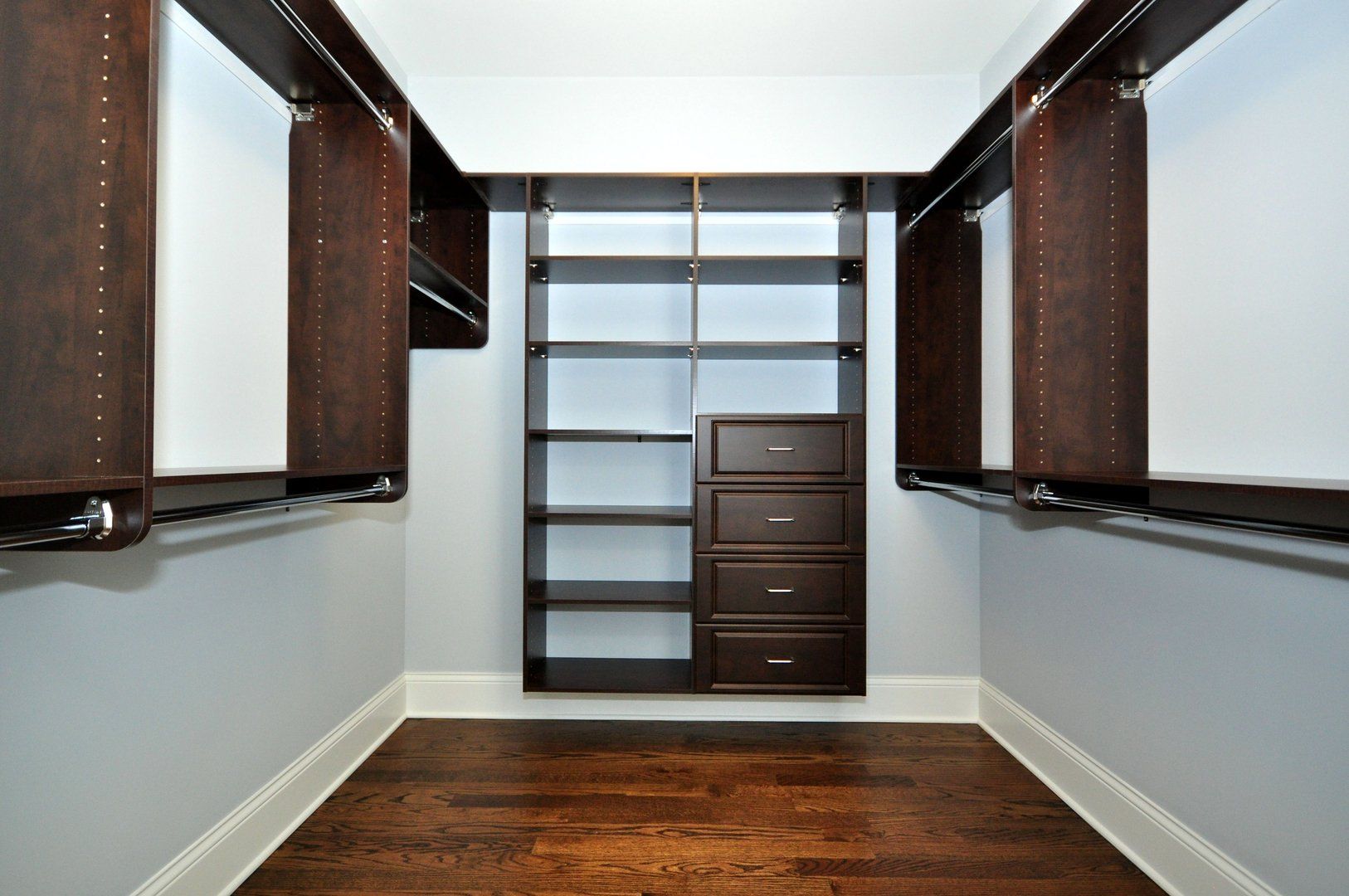 An empty walk in closet with wooden shelves and drawers