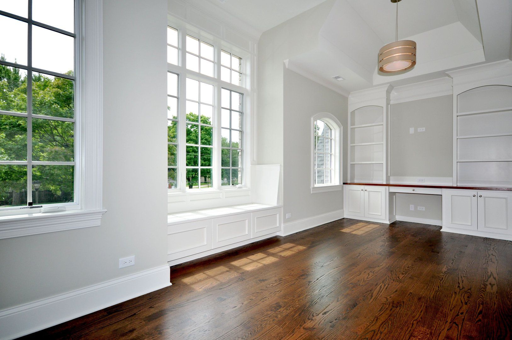 An empty living room with hardwood floors and white walls.