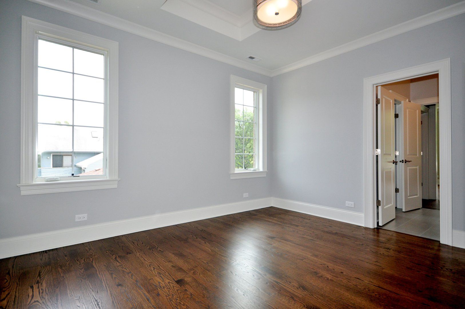 An empty room with hardwood floors and two windows.