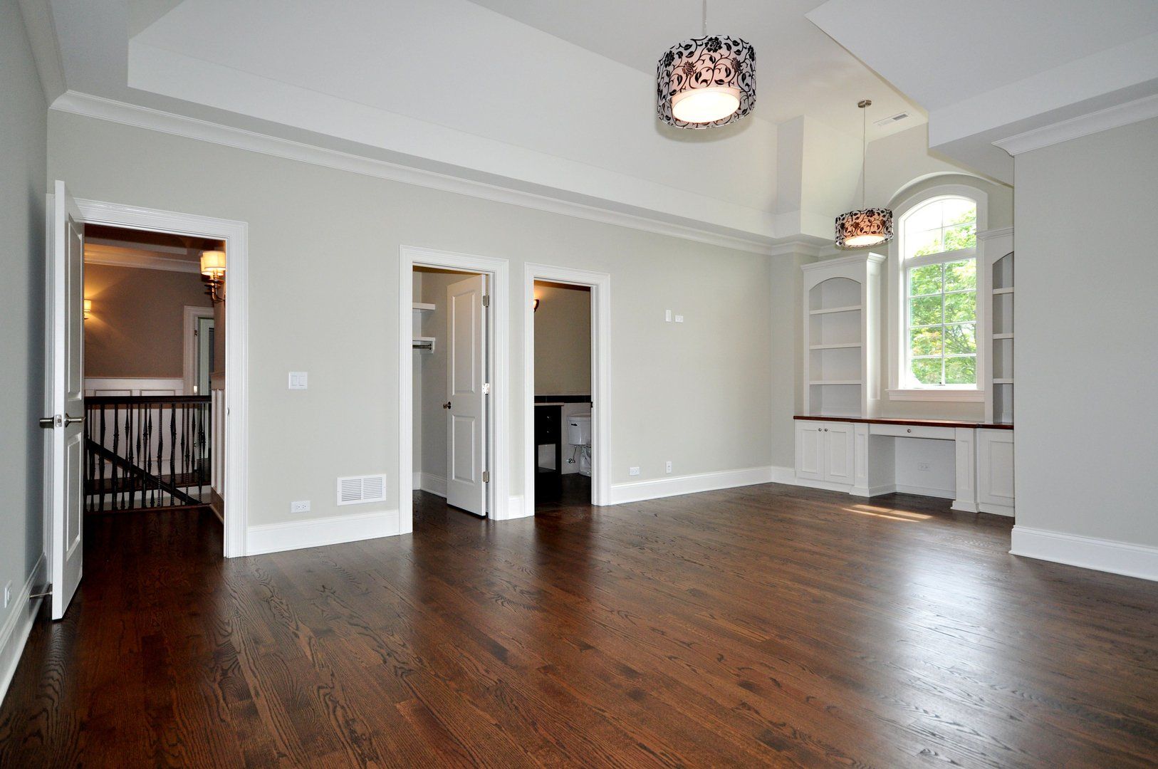 An empty living room with hardwood floors and white walls