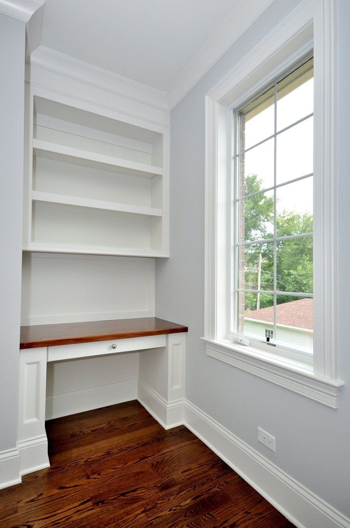 A room with a desk , shelves and a window.