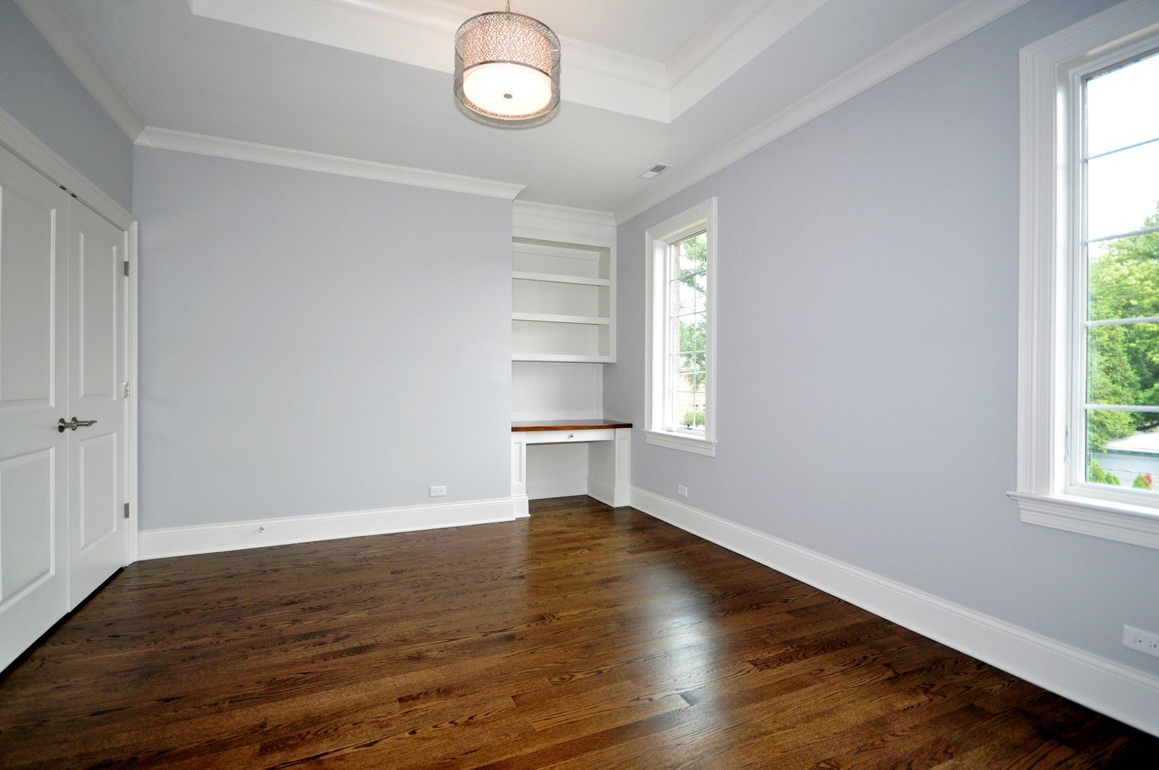 An empty room with hardwood floors and gray walls.