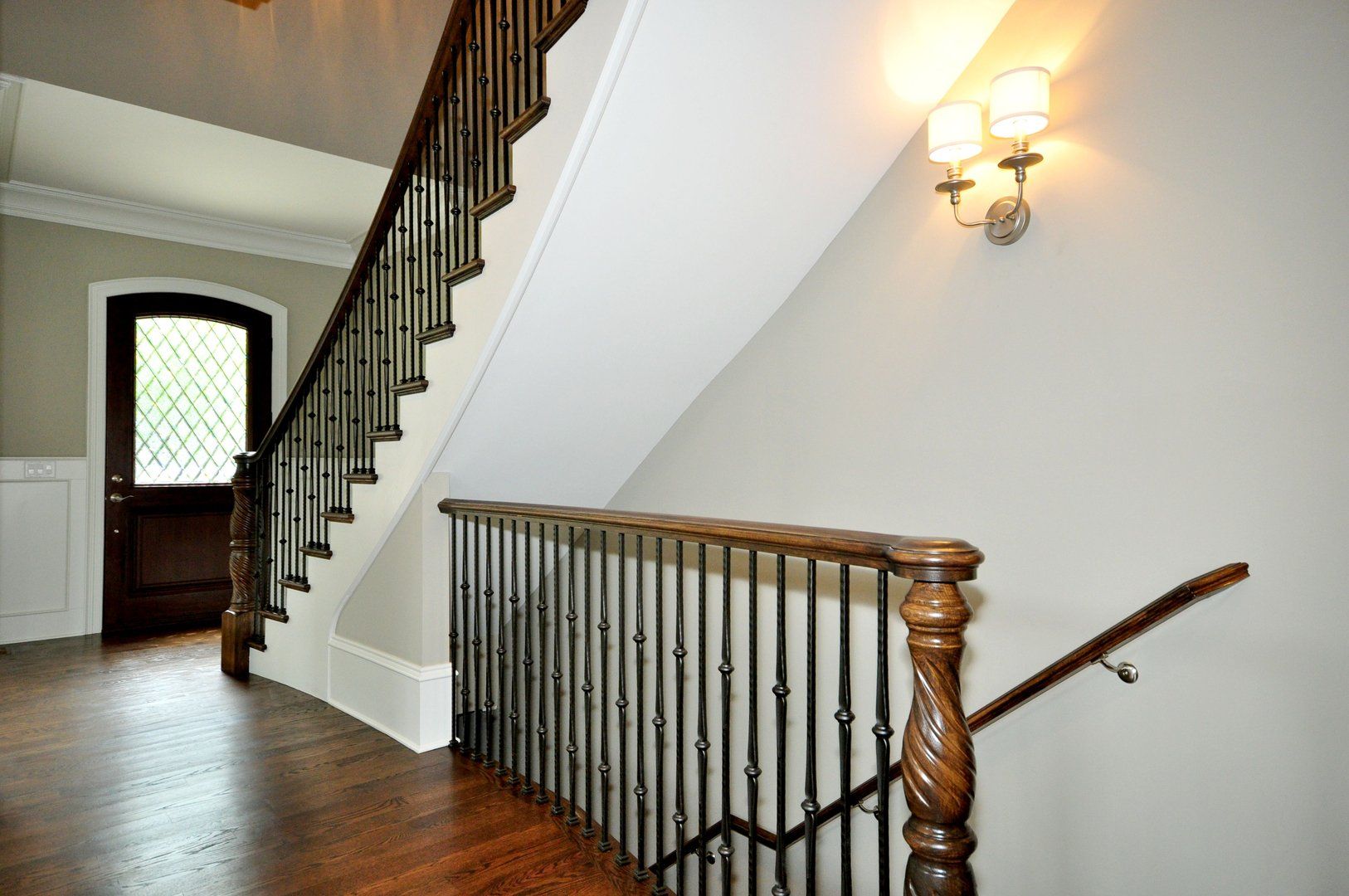 A staircase with a wooden railing and a wrought iron railing