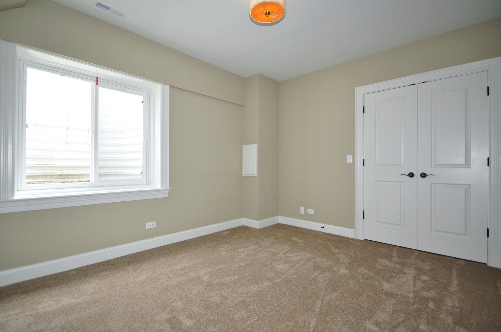 An empty bedroom with a window and a closet.