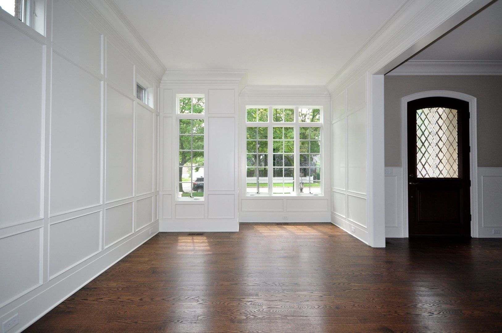 An empty living room with hardwood floors and white walls