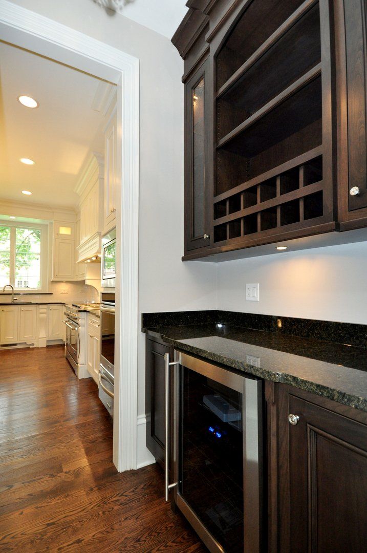 A kitchen with wooden cabinets , granite counter tops , and a wine cooler.