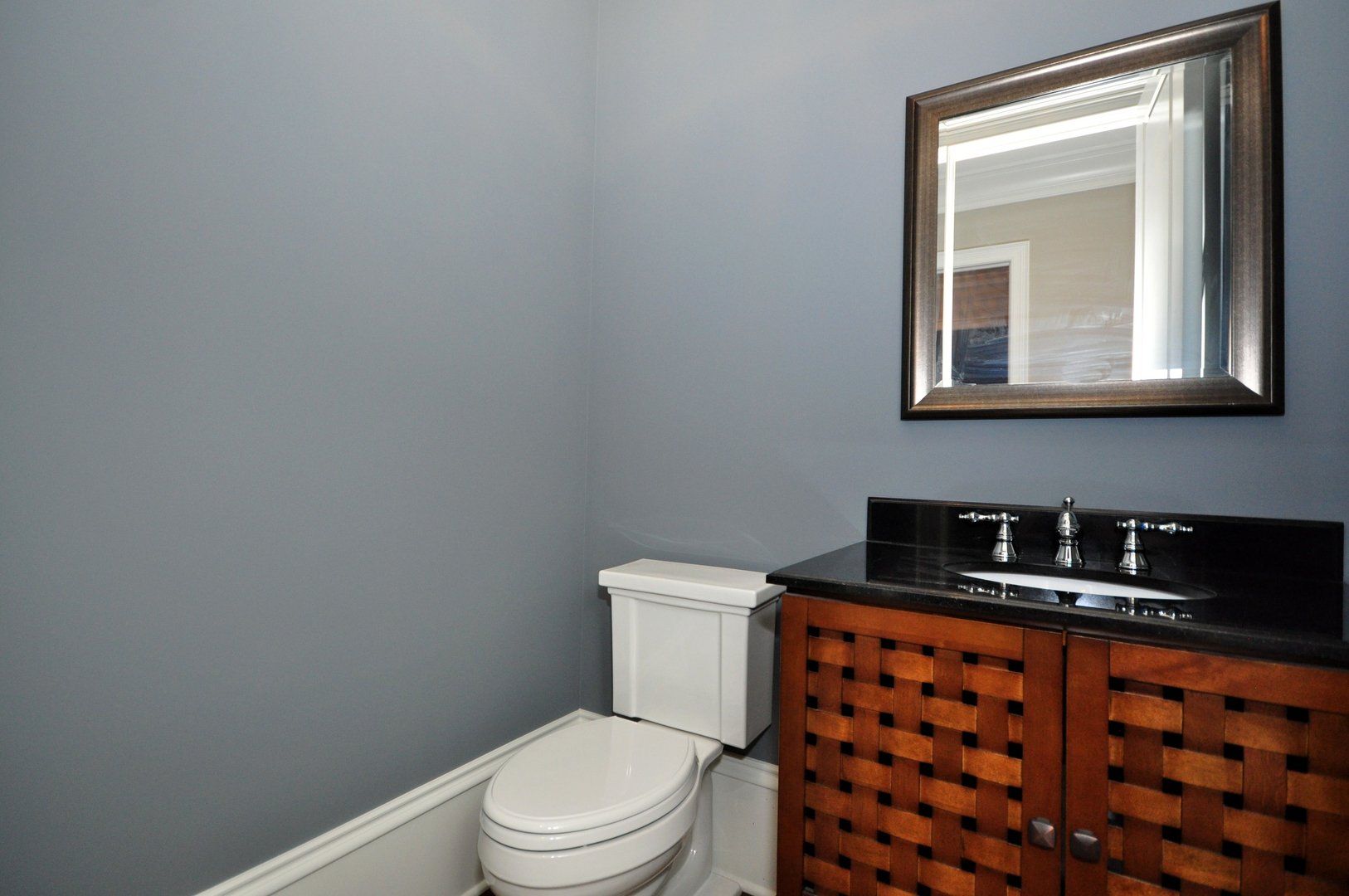 A bathroom with a toilet , sink and mirror.