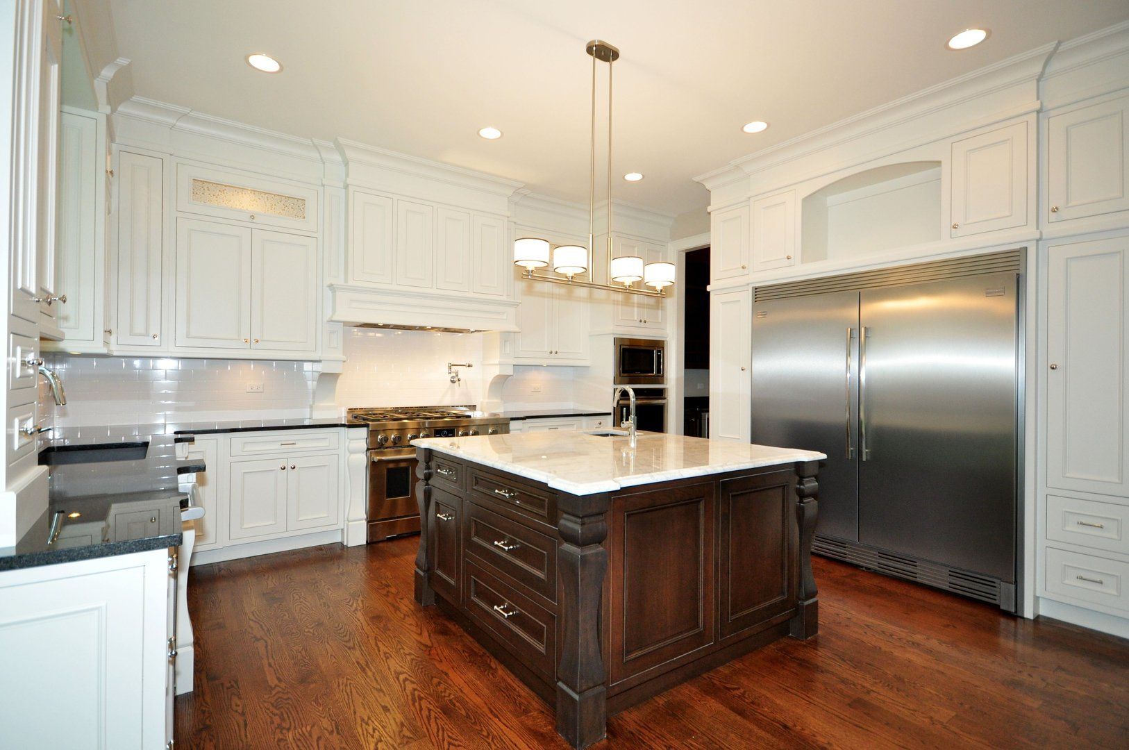 A kitchen with white cabinets and stainless steel appliances and a large island.
