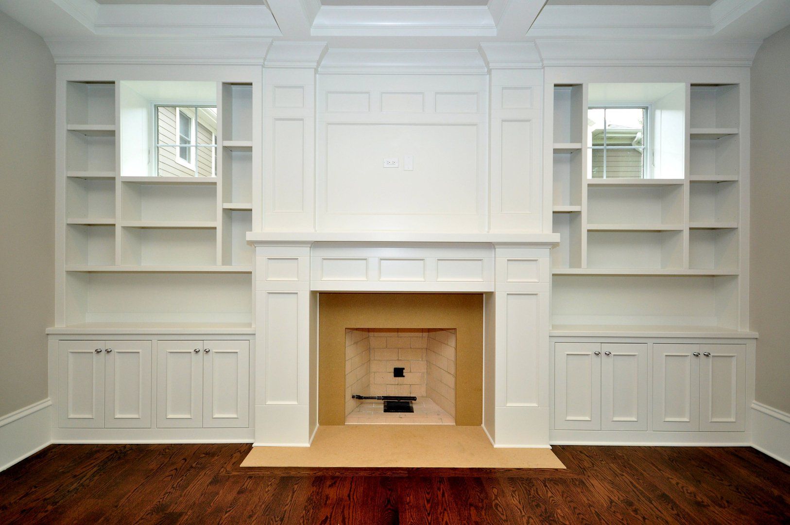 An empty living room with a fireplace and shelves