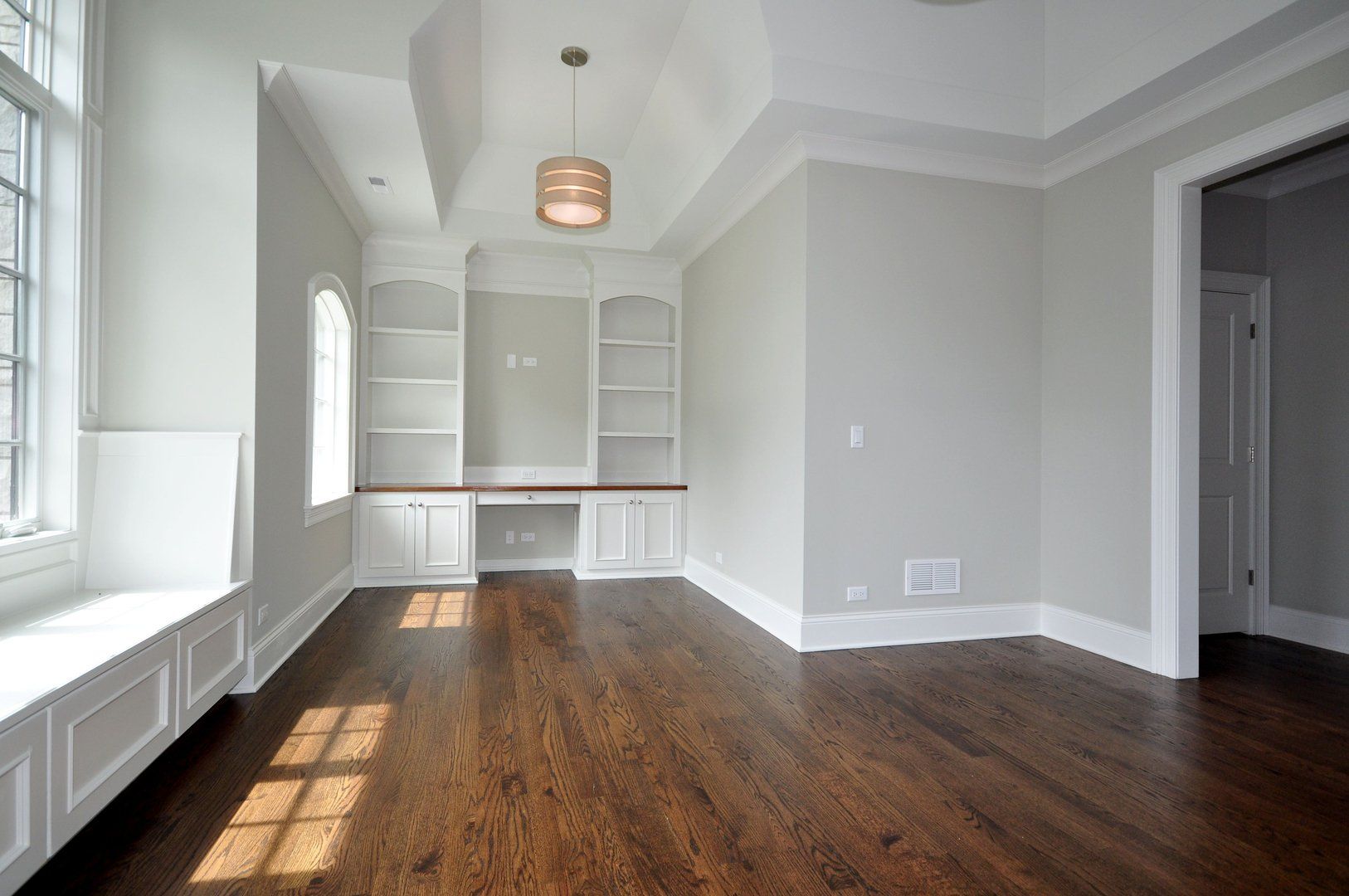 An empty room with hardwood floors and white walls