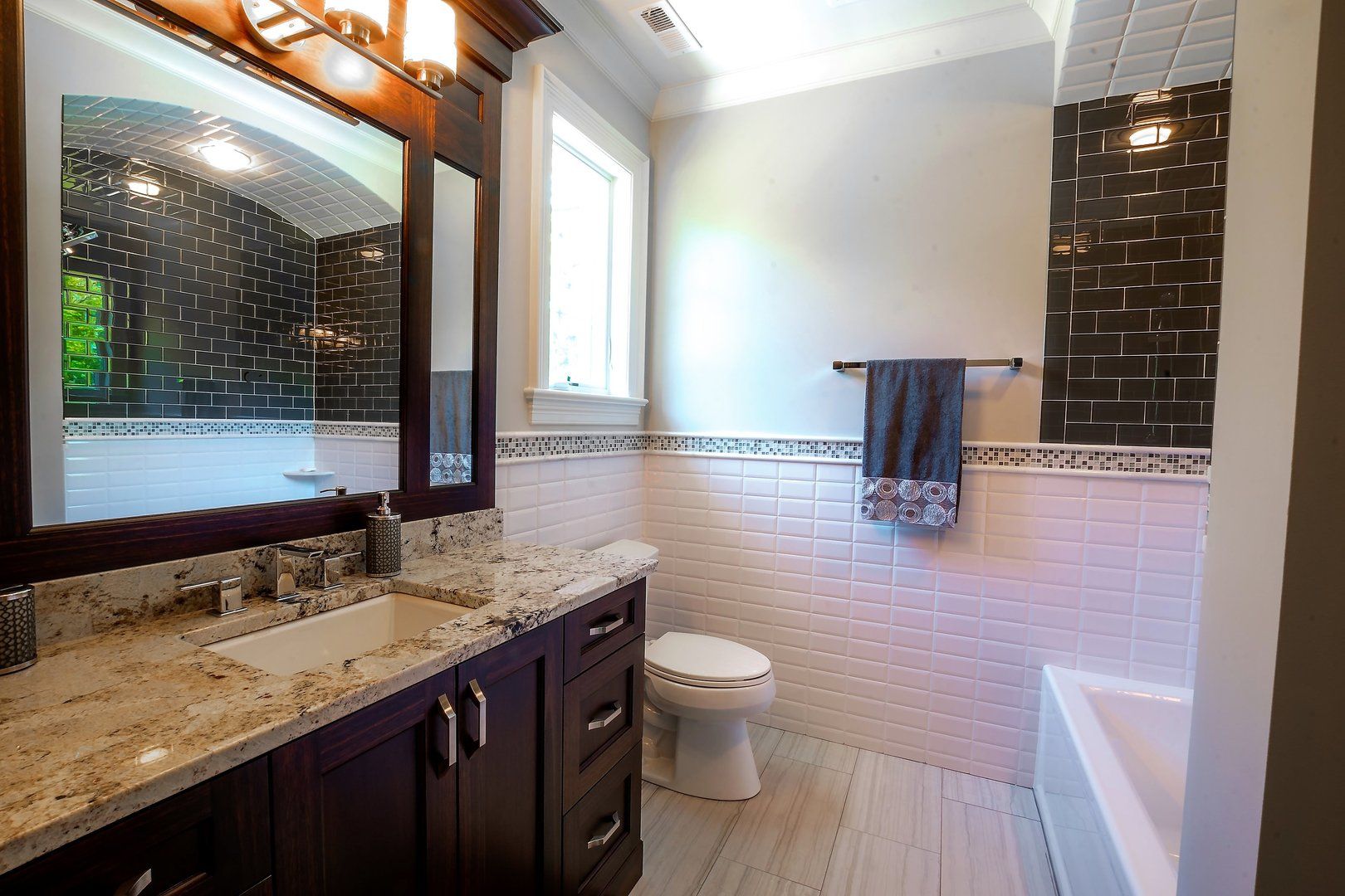 A bathroom with a toilet , sink , mirror and tub.