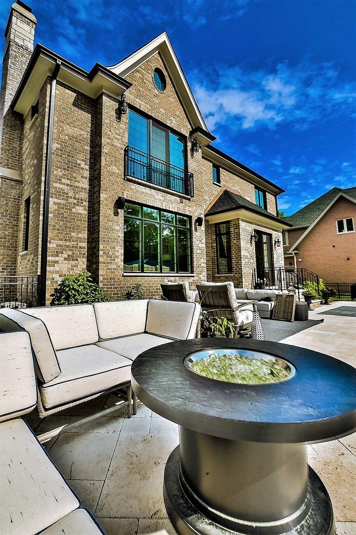 A large brick house with a patio area and a fire pit in front of it.