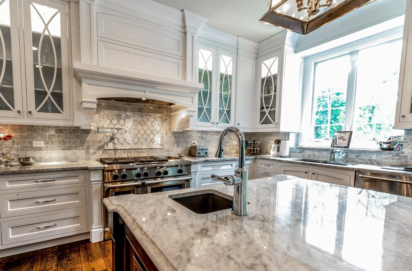 A kitchen with white cabinets , granite counter tops , stainless steel appliances , a sink and a stove.