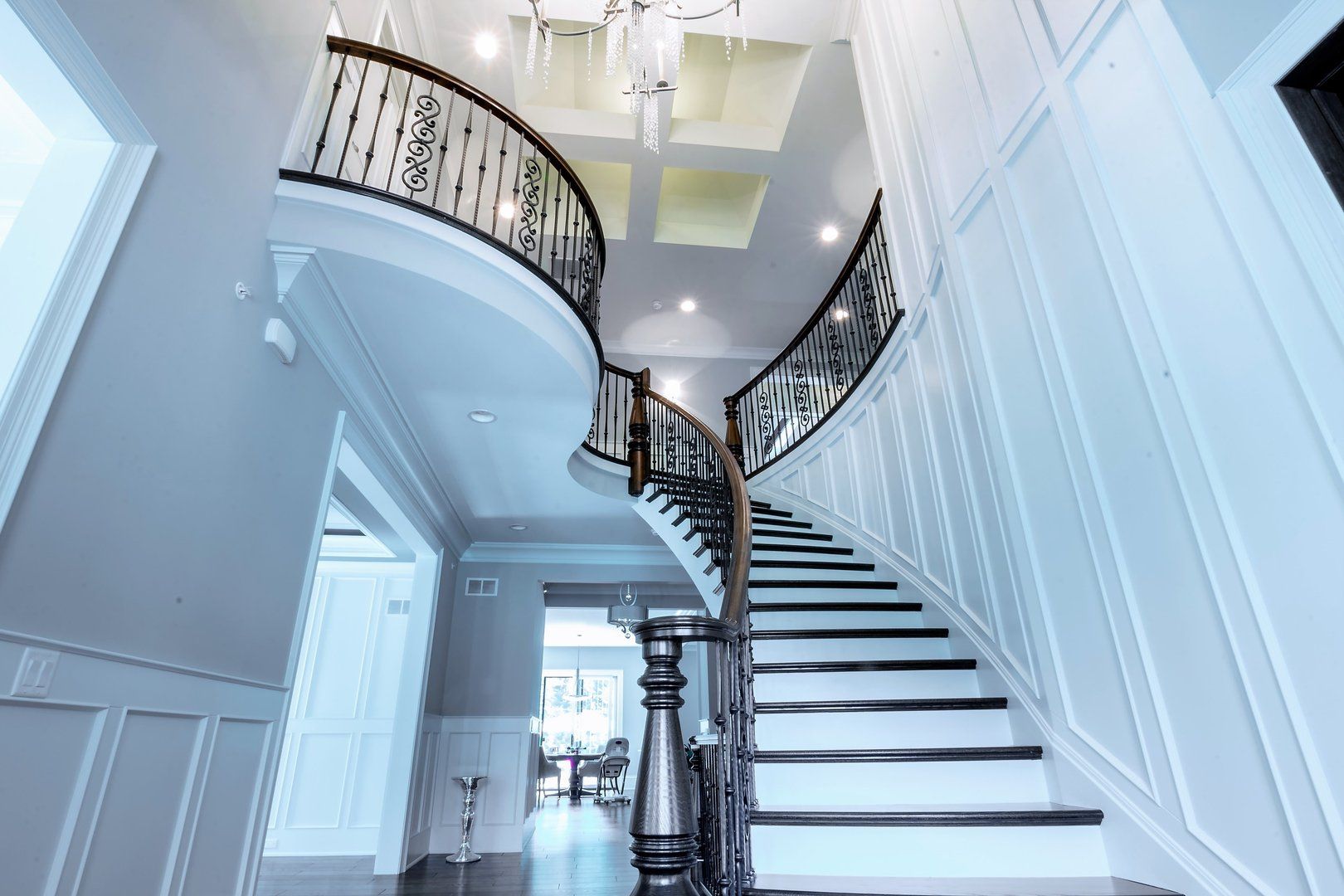 A large curved staircase in a house with a chandelier hanging from the ceiling.