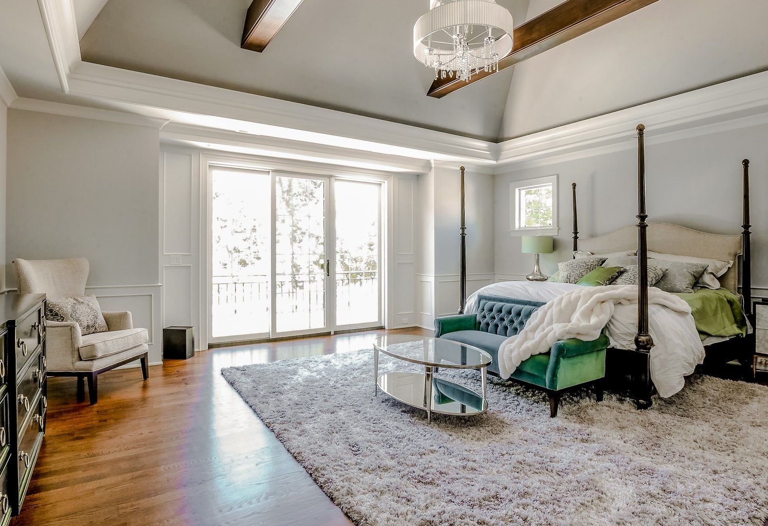 A large bedroom with a four poster bed , couch , chair and rug.