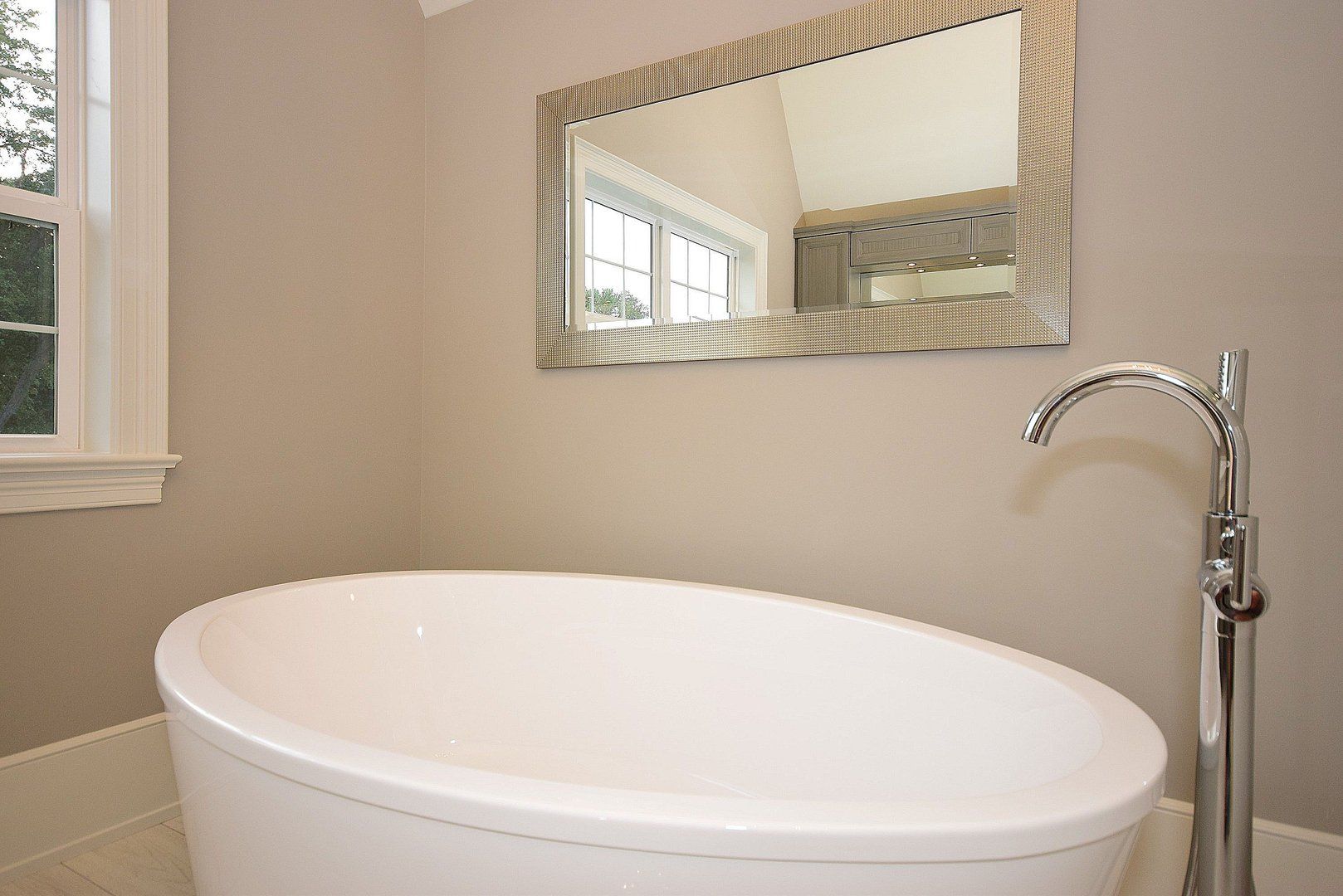 A bathroom with a bathtub and a mirror on the wall