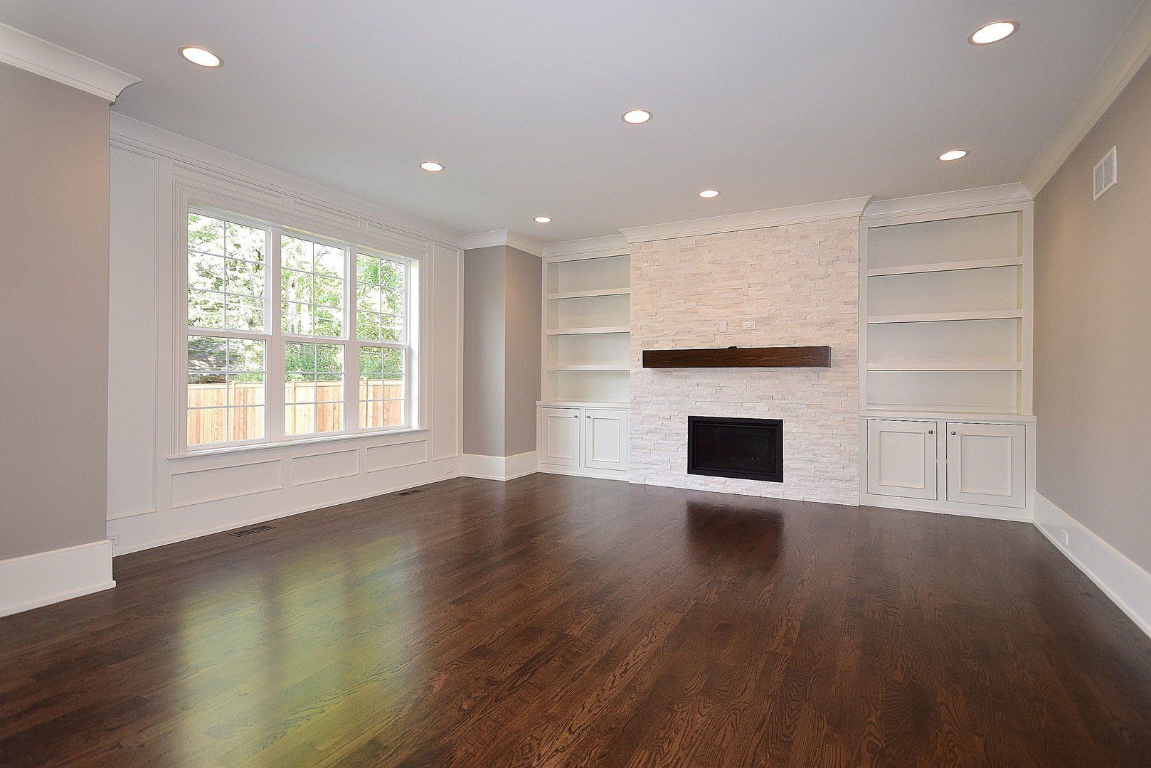An empty living room with hardwood floors and a fireplace.