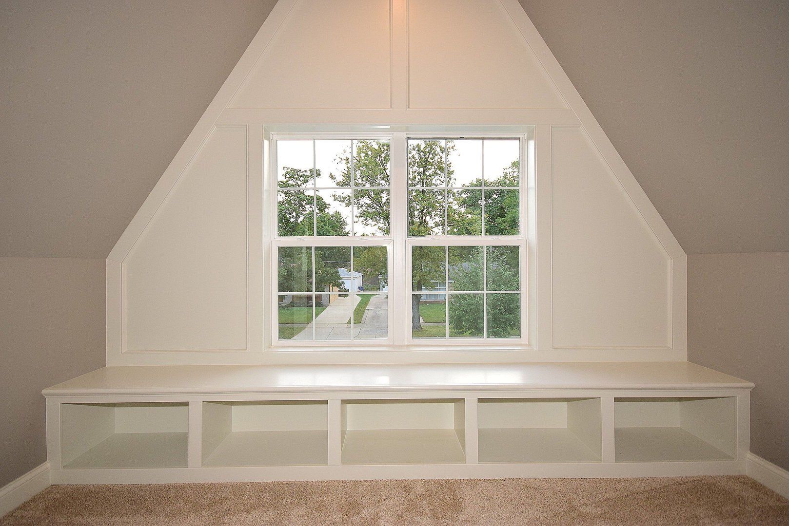 A room with a window and a bench with shelves underneath it