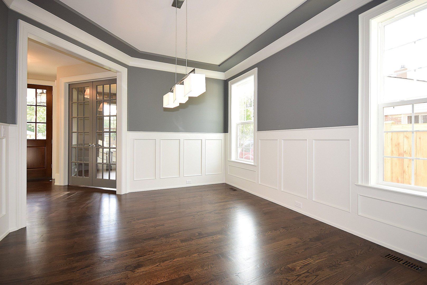 An empty dining room with hardwood floors and gray walls