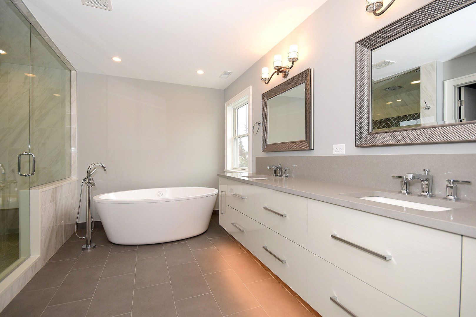 A bathroom with two sinks , a tub , and a mirror.
